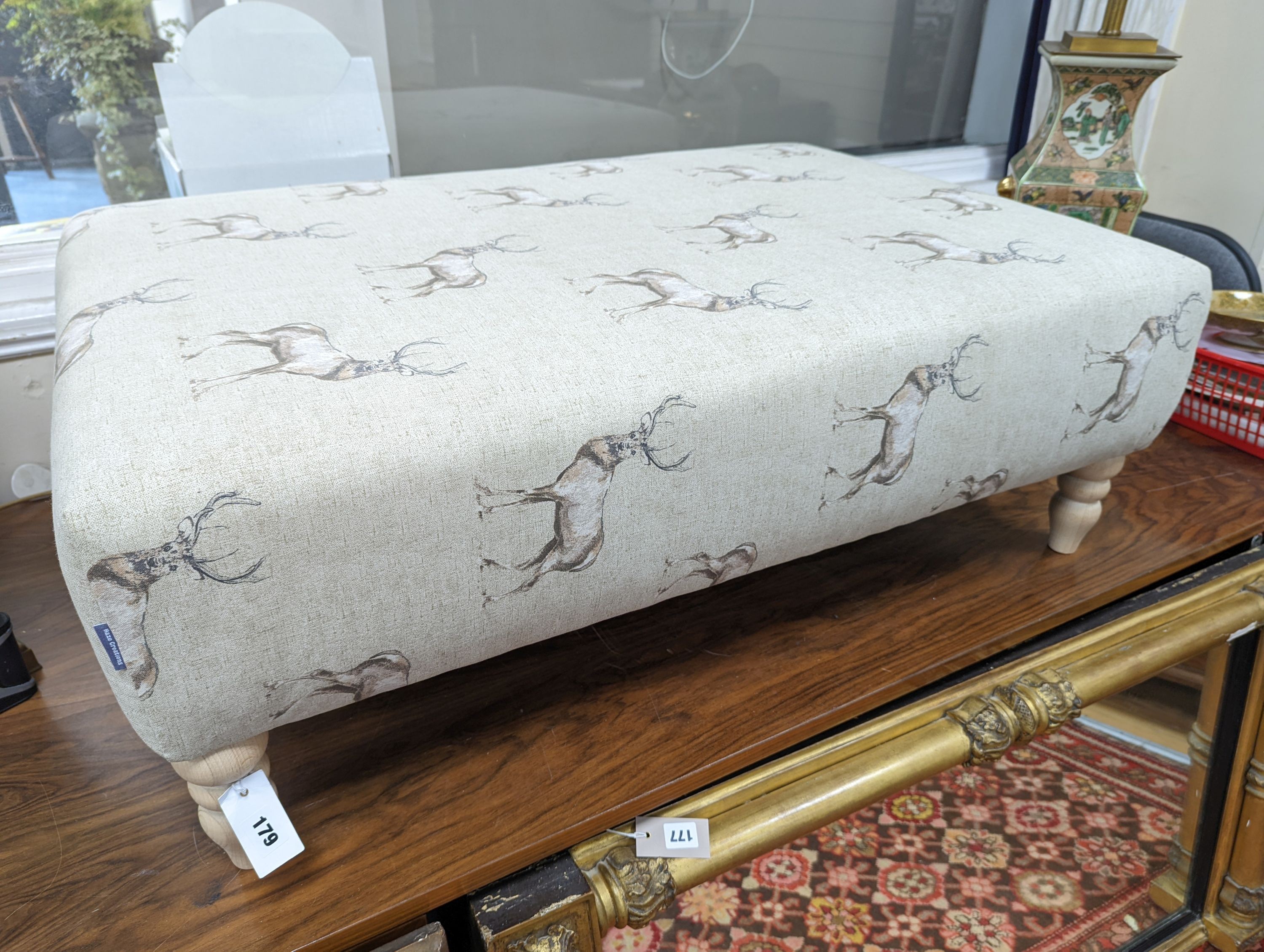 A large contemporary rectangular footstool / coffee table upholstered in stag print fabric on turned beech feet, length 107cm, depth 72cm, height 38cm